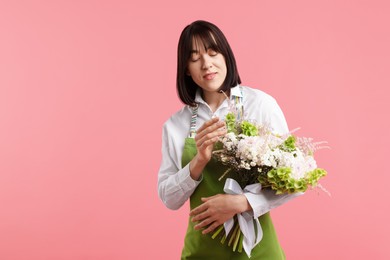 Photo of Florist with beautiful bouquet of flowers on pink background, space for text