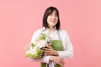 Photo of Florist with beautiful bouquet of flowers on pink background