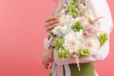 Photo of Florist with beautiful bouquet of flowers on pink background, closeup. Space for text