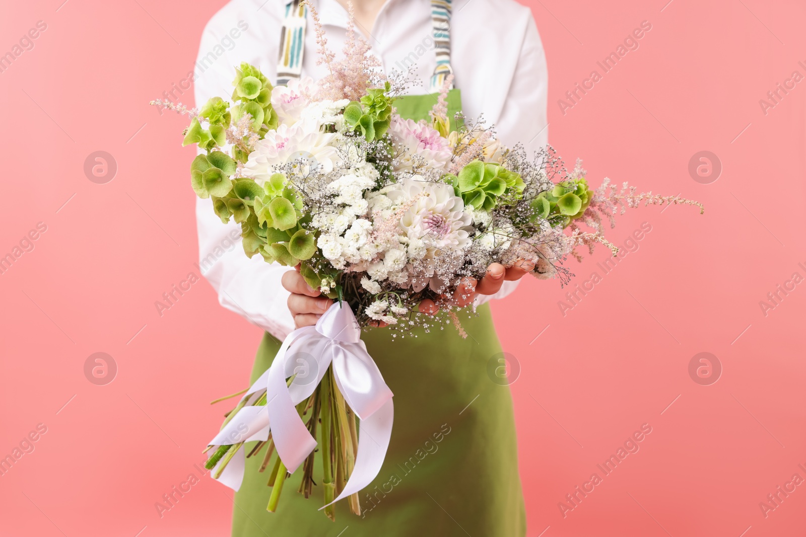 Photo of Florist with beautiful bouquet of flowers on pink background, closeup