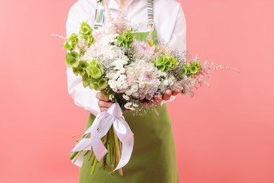 Photo of Florist with beautiful bouquet of flowers on pink background, closeup