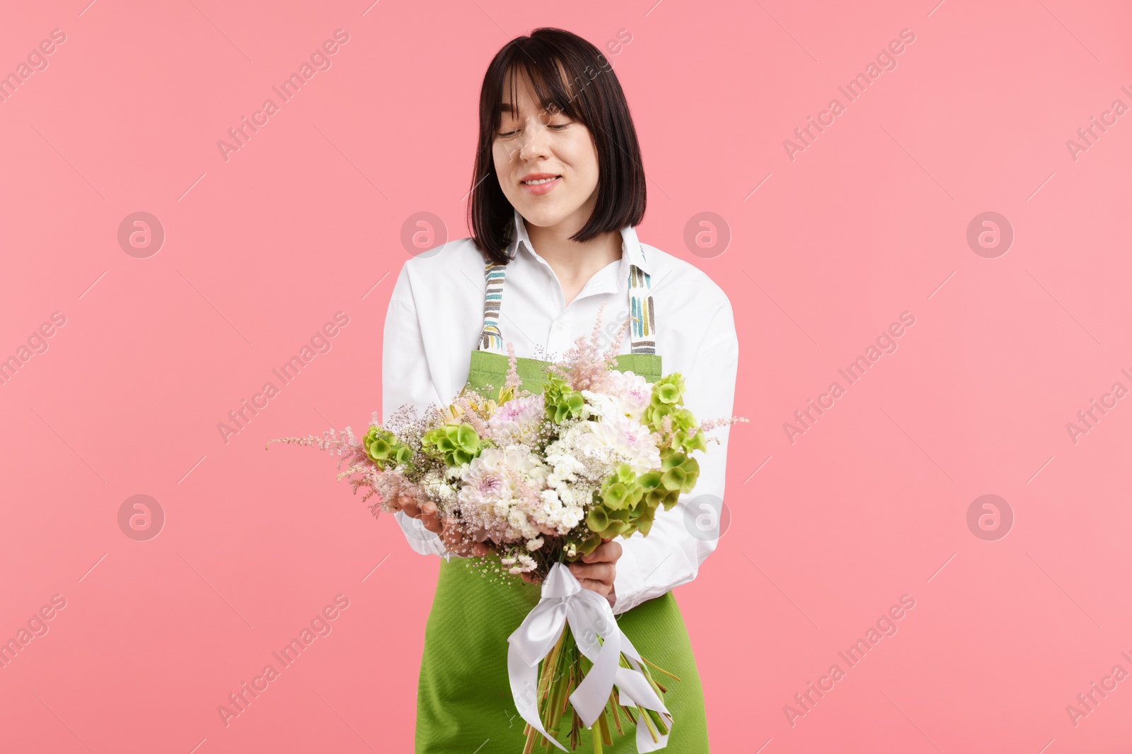 Photo of Florist with beautiful bouquet of flowers on pink background