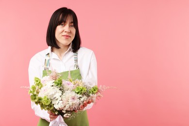 Photo of Florist with beautiful bouquet of flowers on pink background, space for text