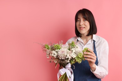 Photo of Florist with beautiful bouquet of flowers on pink background, space for text