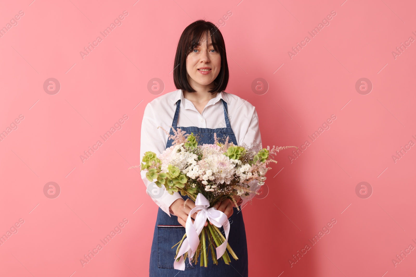 Florist with beautiful bouquet of flowers on pink background Photo of Florist with beautiful bouquet of flowers on pink background