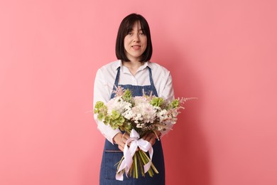 Photo of Florist with beautiful bouquet of flowers on pink background