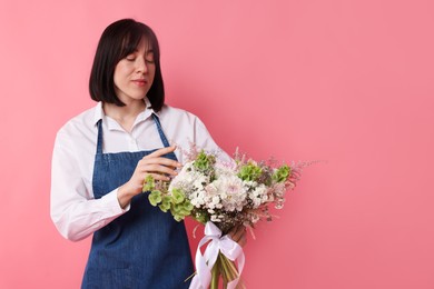 Photo of Florist with beautiful bouquet of flowers on pink background, space for text