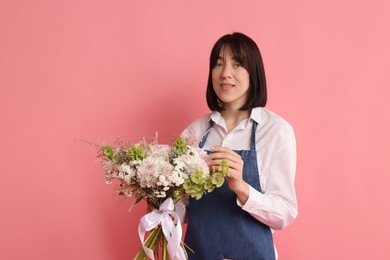Photo of Florist with beautiful bouquet of flowers on pink background