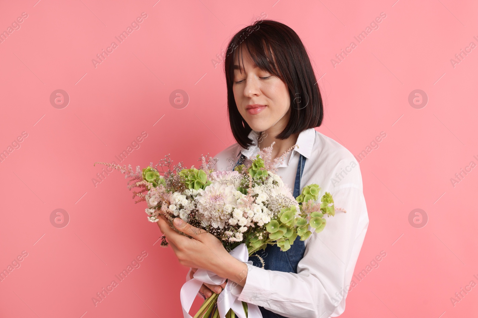 Florist with beautiful bouquet of flowers on pink background Photo of Florist with beautiful bouquet of flowers on pink background