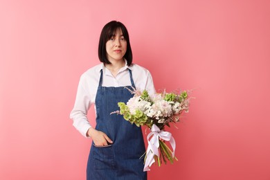 Photo of Florist with beautiful bouquet of flowers on pink background