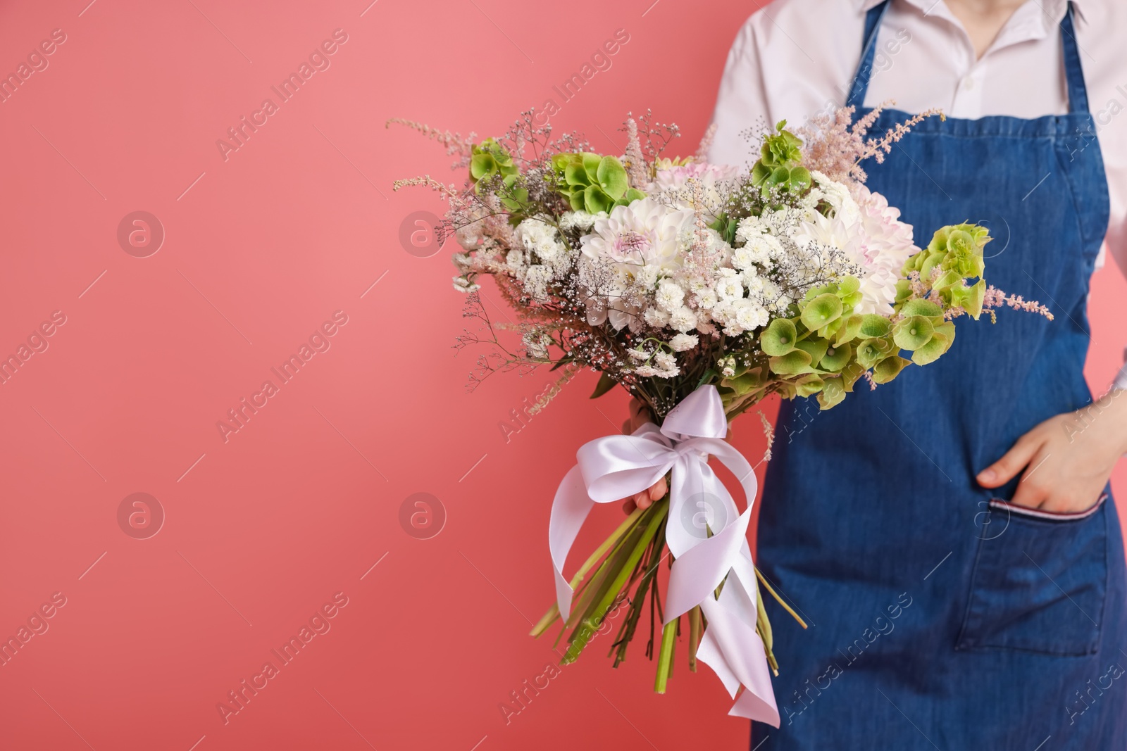Florist with beautiful bouquet of flowers on pink background, closeup. Space for text Photo of Florist with beautiful bouquet of flowers on pink background, closeup. Space for text