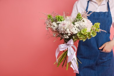 Photo of Florist with beautiful bouquet of flowers on pink background, closeup. Space for text