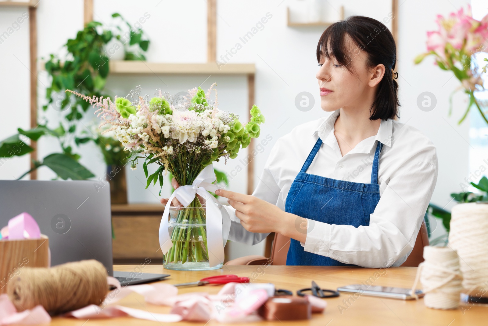 Florist making bouquet of flowers at wooden table indoors Photo of Florist making bouquet of flowers at wooden table indoors