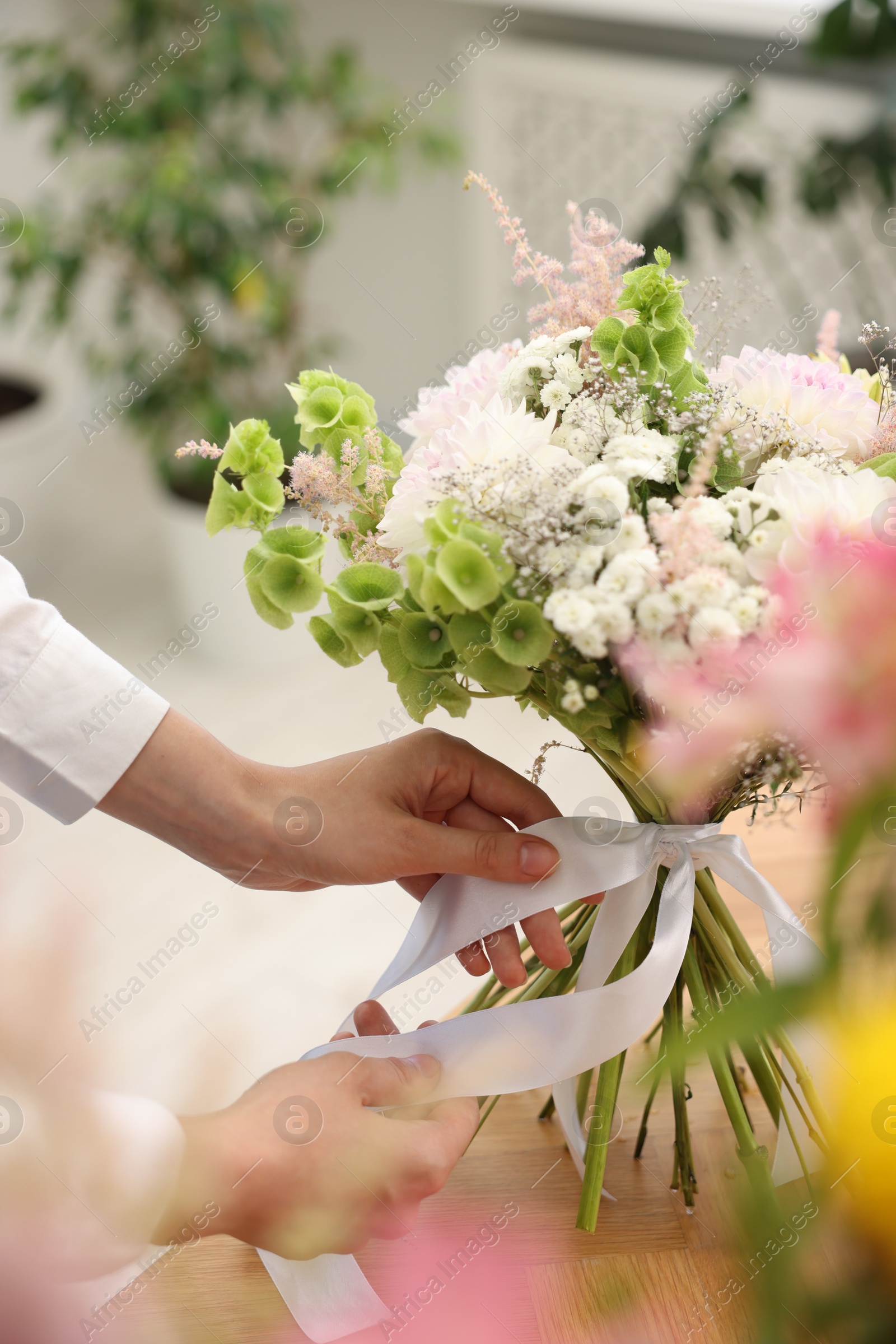 Florist making bouquet of flowers at table indoors, closeup Photo of Florist making bouquet of flowers at table indoors, closeup