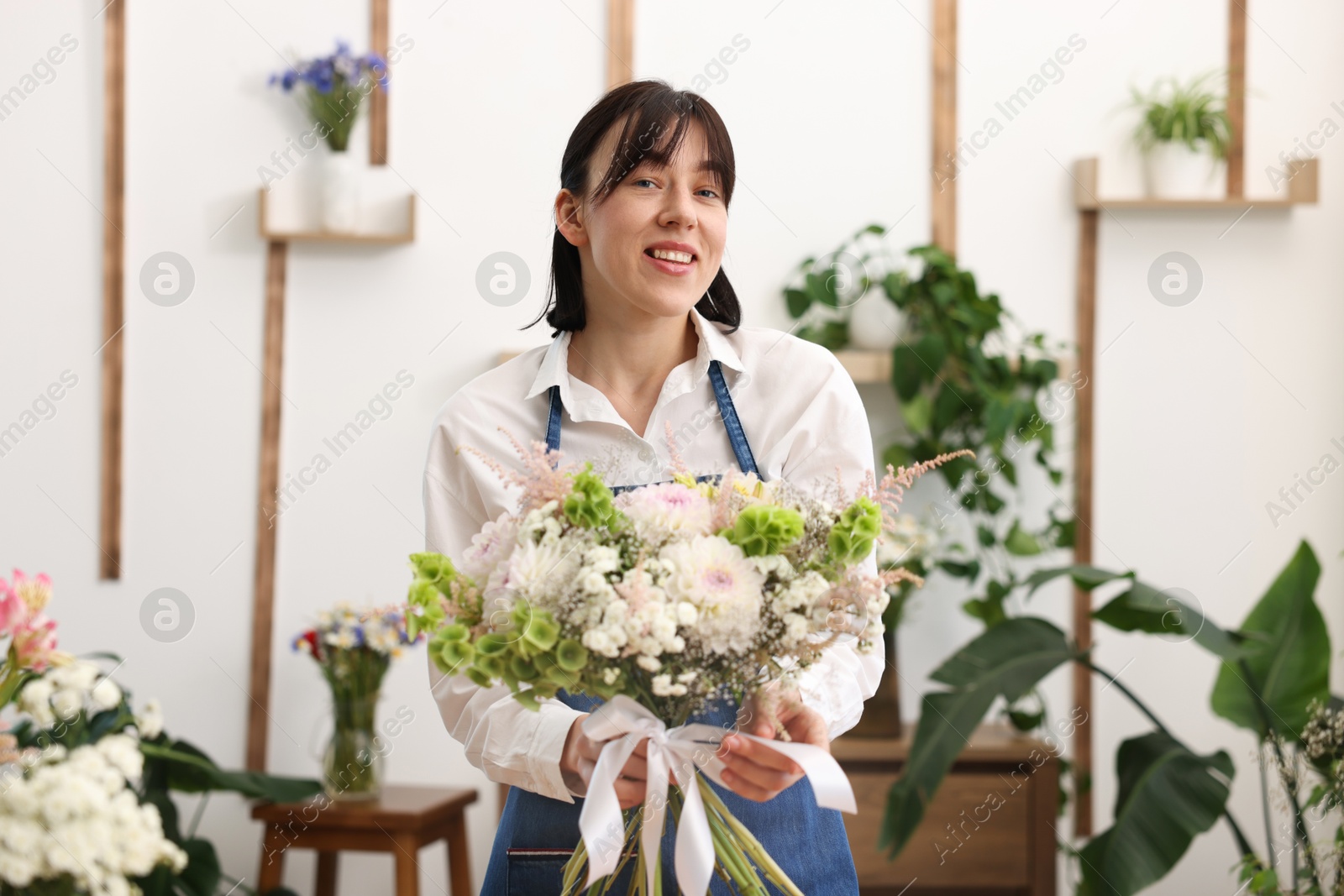 Photo of Florist with beautiful bouquet of flowers indoors