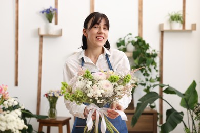 Photo of Florist with beautiful bouquet of flowers indoors