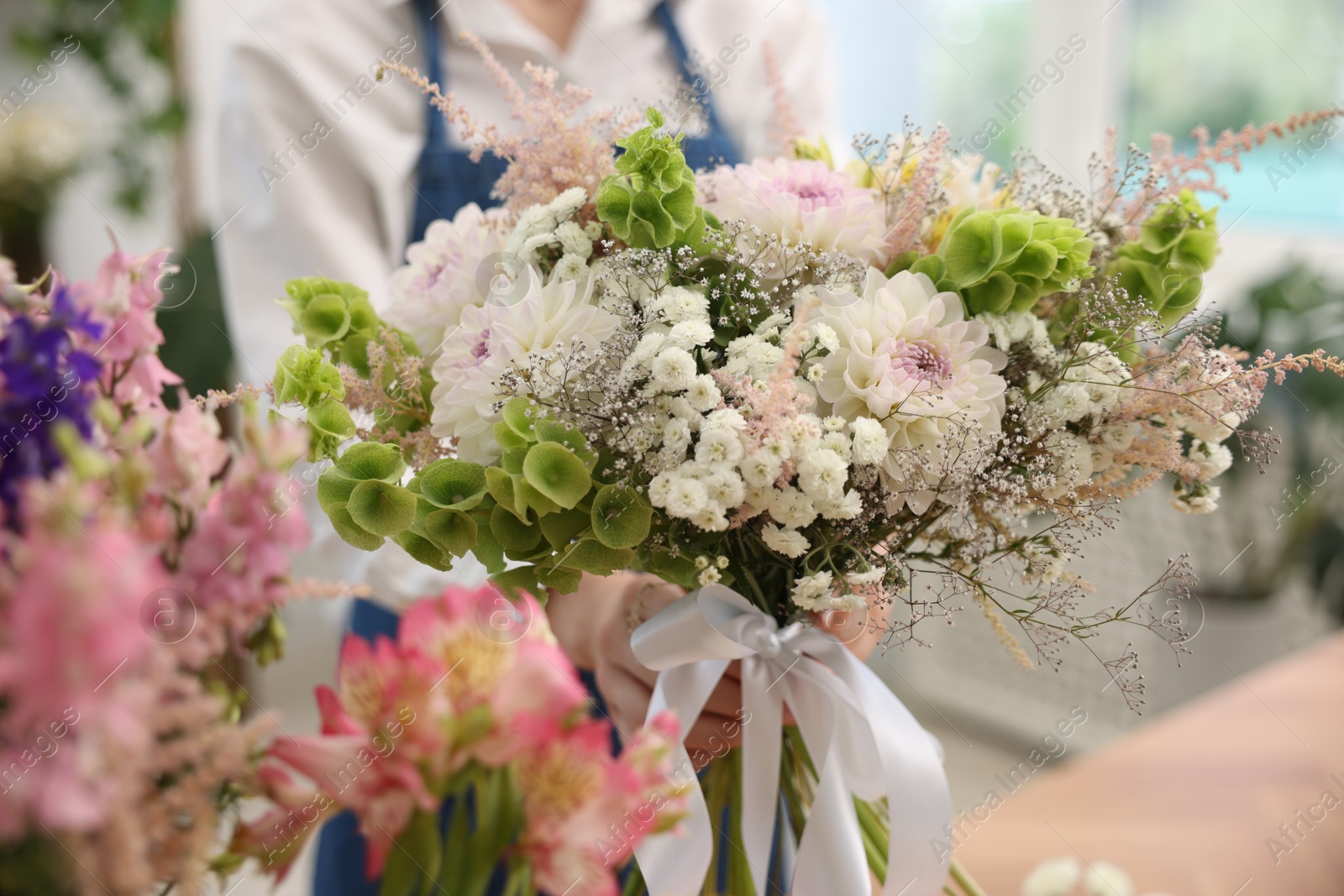 Florist with beautiful bouquet of flowers indoors, selective focus Photo of Florist with beautiful bouquet of flowers indoors, selective focus