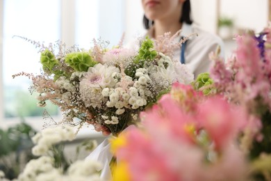 Photo of Florist with beautiful bouquet of flowers indoors, selective focus