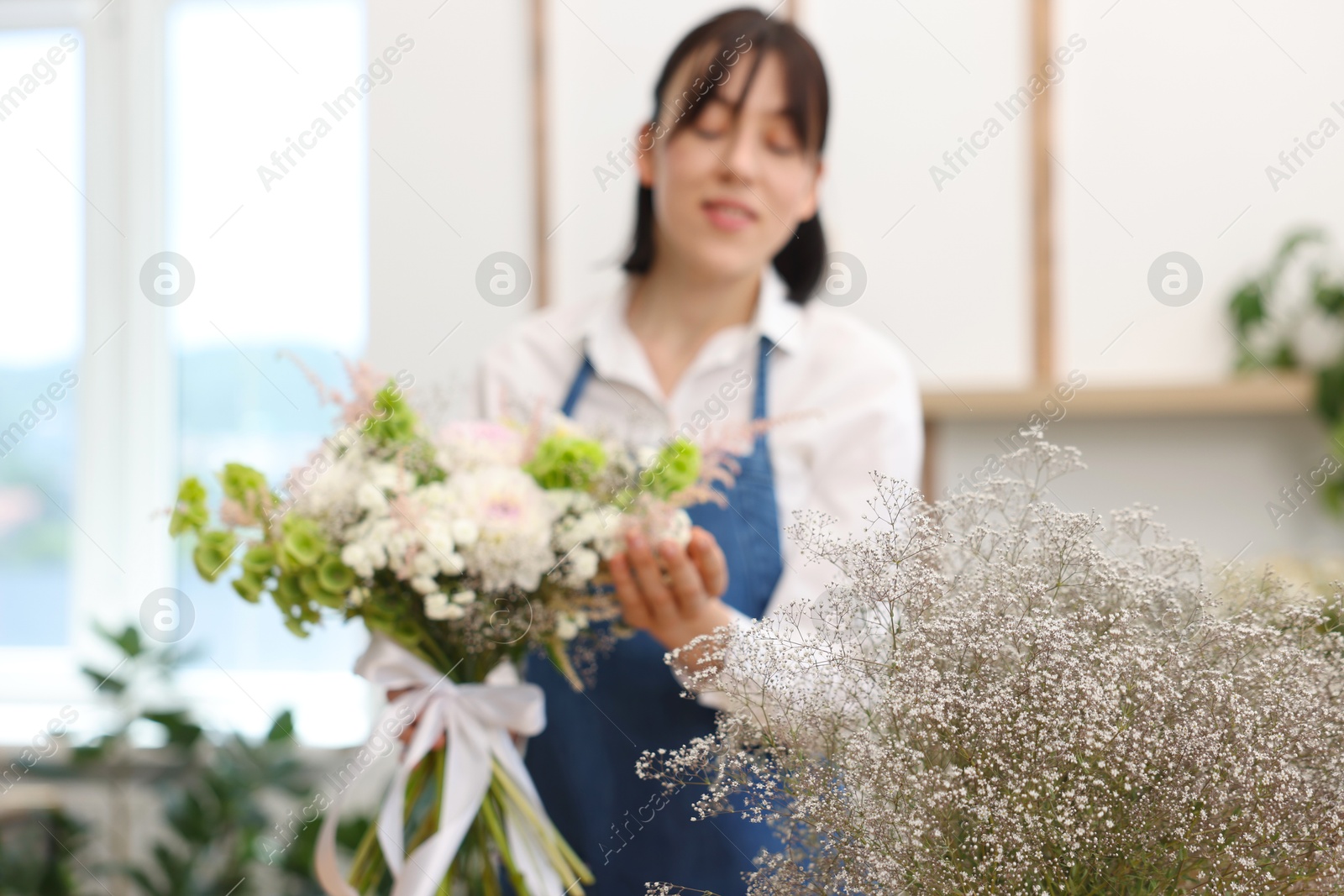 Photo of Florist with beautiful bouquet of flowers indoors, selective focus