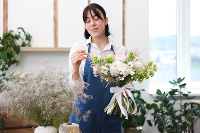 Photo of Florist with beautiful bouquet of flowers indoors