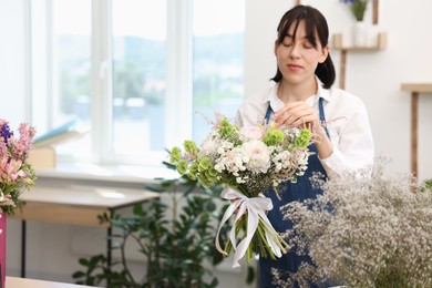 Photo of Florist with beautiful bouquet of flowers indoors, space for text