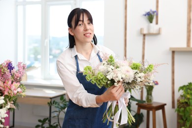Photo of Florist with beautiful bouquet of flowers indoors