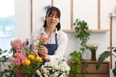 Photo of Florist making bouquet of flowers in shop, space for text