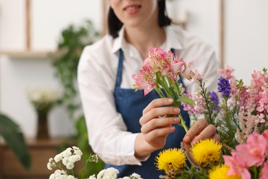 Photo of Florist making bouquet of flowers indoors, closeup