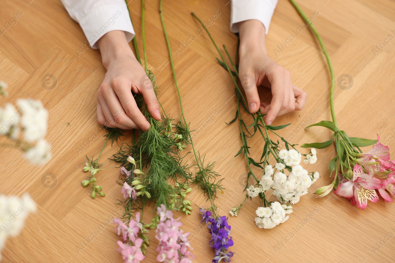 Florist making bouquet of flowers at wooden table, above view Photo of Florist making bouquet of flowers at wooden table, above view