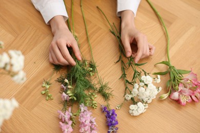 Photo of Florist making bouquet of flowers at wooden table, above view