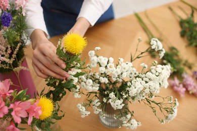 Photo of Florist making bouquet of flowers at wooden table, above view