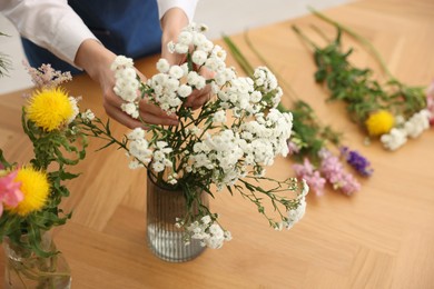 Photo of Florist making bouquet of flowers at wooden table, above view
