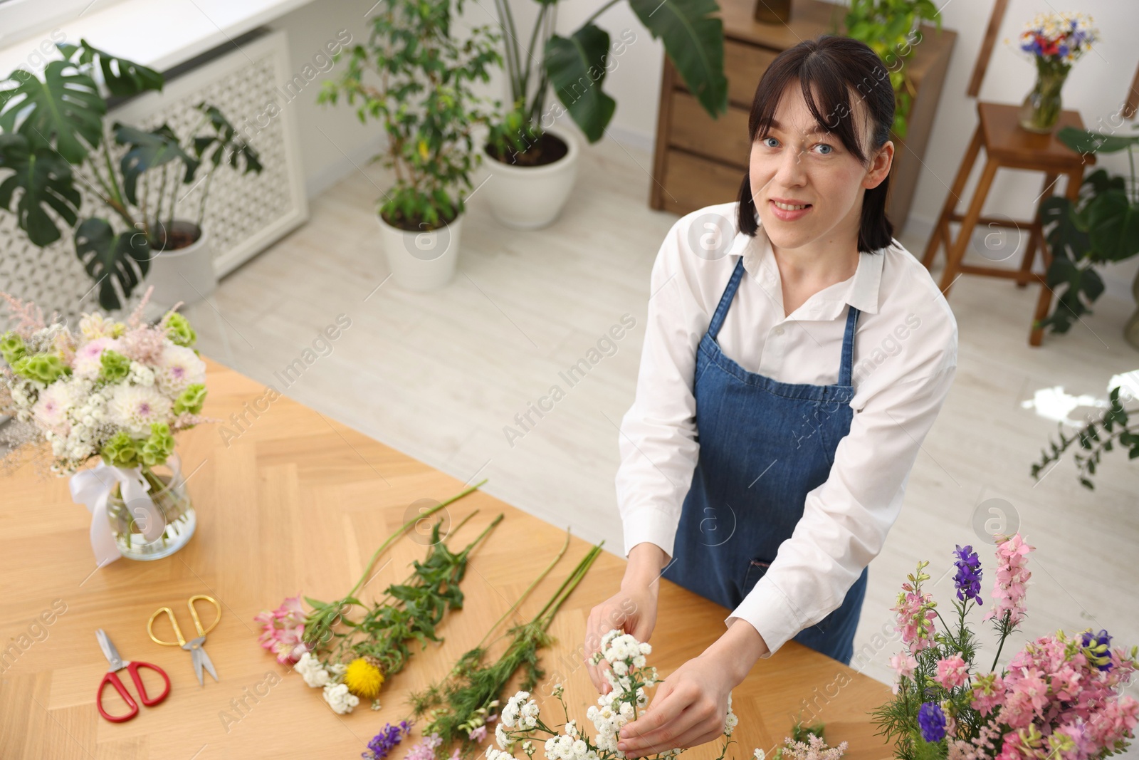 Florist making bouquet of flowers at wooden table, above view Photo of Florist making bouquet of flowers at wooden table, above view