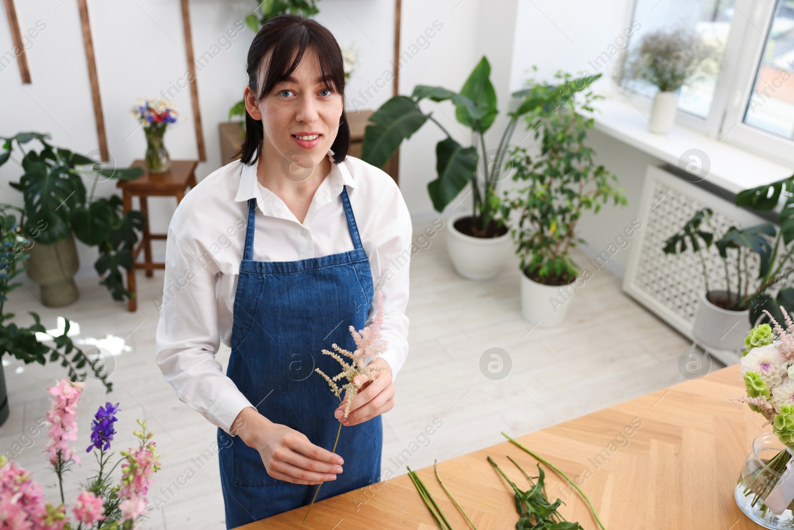 Florist making bouquet of flowers at wooden table, above view Photo of Florist making bouquet of flowers at wooden table, above view