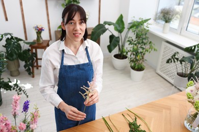 Photo of Florist making bouquet of flowers at wooden table, above view