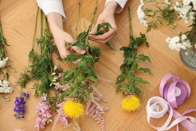 Photo of Florist making bouquet of flowers at wooden table, top view