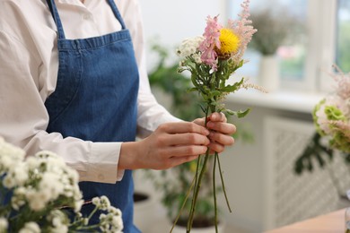 Photo of Florist making bouquet of flowers in shop, closeup