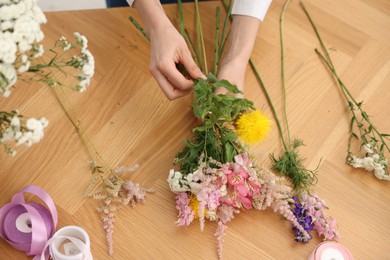 Photo of Florist making bouquet of flowers at wooden table, top view