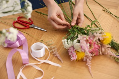 Photo of Florist making bouquet of flowers at wooden table, closeup
