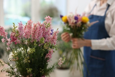 Photo of Florist making bouquet of flowers in shop, selective focus