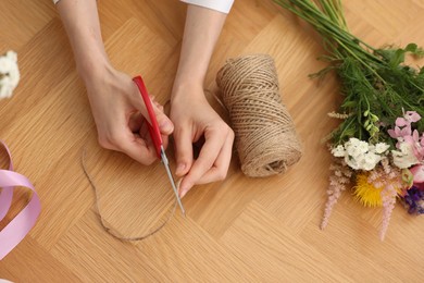 Photo of Florist making bouquet of flowers at wooden table, top view