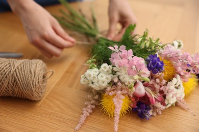 Photo of Florist making bouquet of flowers at wooden table, closeup