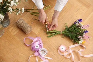 Photo of Florist making bouquet of flowers at wooden table, top view