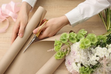 Photo of Florist making bouquet of flowers at wooden table, above view