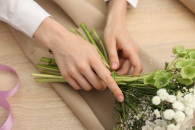 Photo of Florist making bouquet of flowers at wooden table, closeup