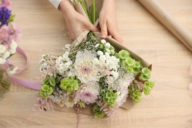 Photo of Florist making bouquet of flowers at wooden table, above view