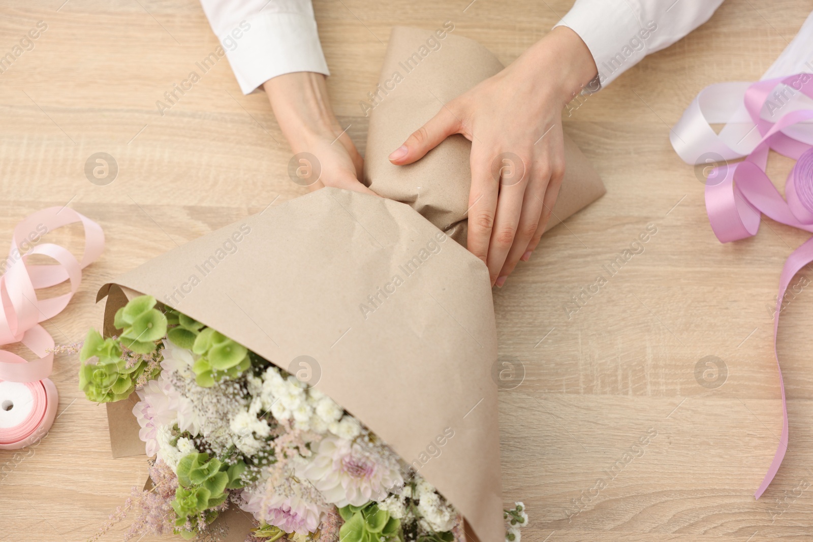 Florist making bouquet of flowers at wooden table, top view Photo of Florist making bouquet of flowers at wooden table, top view
