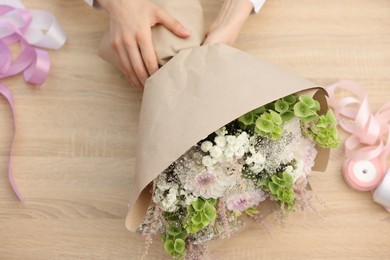 Photo of Florist making bouquet of flowers at wooden table, above view
