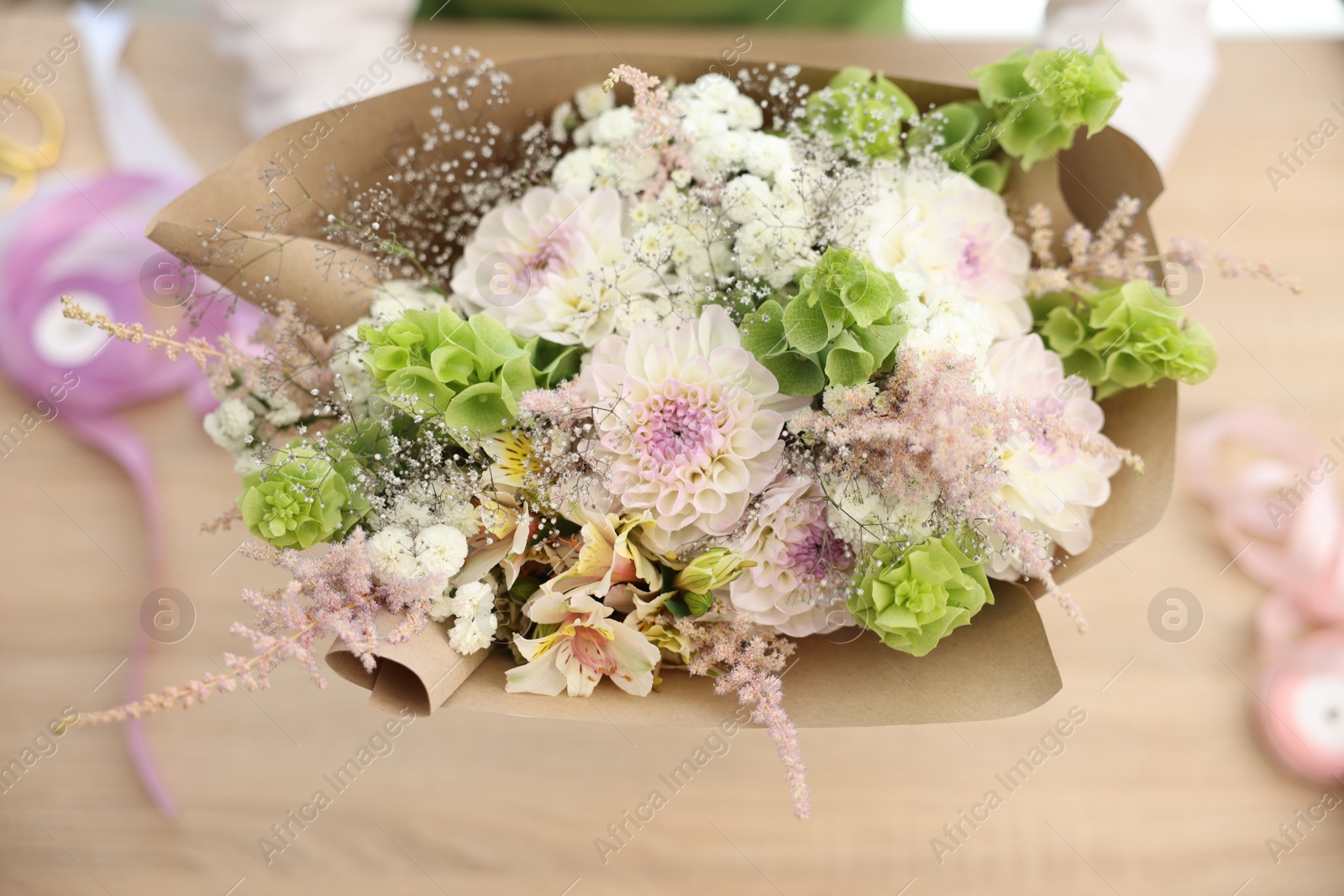 Photo of Florist making bouquet of flowers at table, selective focus
