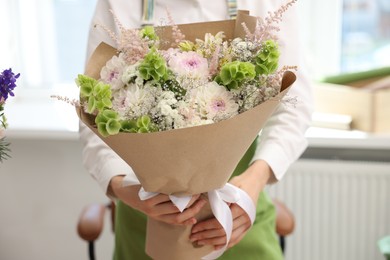 Photo of Florist with beautiful bouquet of flowers indoors, closeup